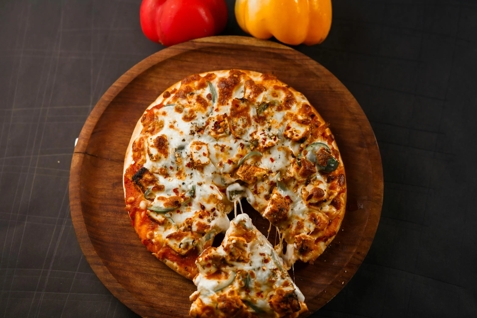 Cheese pizza topped with grilled vegetables and spices on a wooden board
