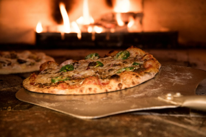 Wood fired oven baking a traditional pizza with crispy crust, mozzarella cheese, and fresh toppings 