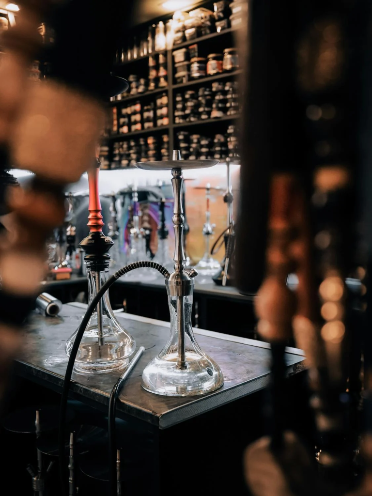 Modern hookah setup in a Dubai shisha lounge with shelves of tobacco flavors